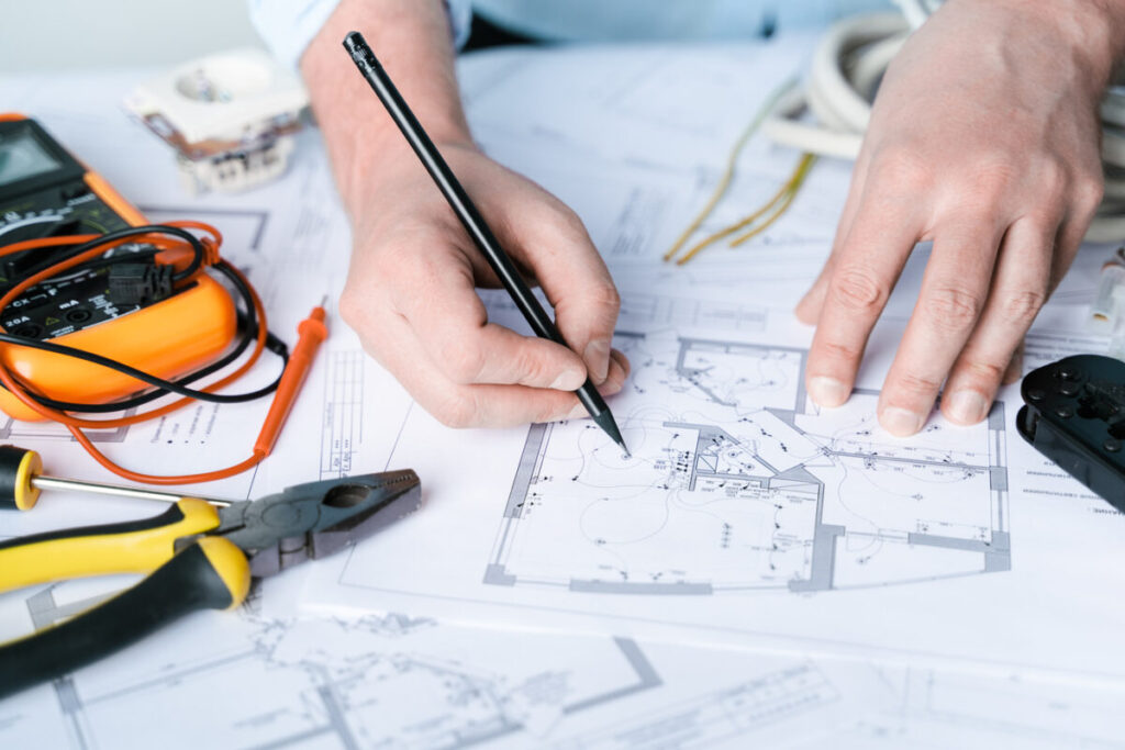 Man,repairer making electricity project in house.Repairs planning.Drawings,diagrams,plan for electrification of apartment,building.Devices,accessories,voltmeter,wires,screwdriver,pliers,tape measure